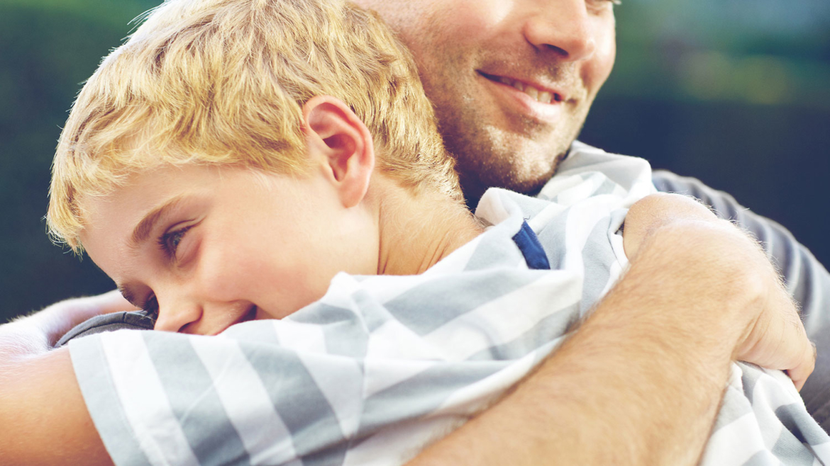 Na zdjęciu syn przytulający ojca